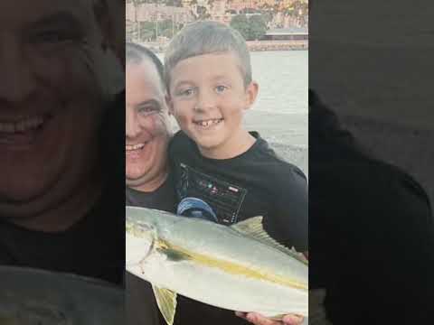 Seven year-old catches a yellowtail fishing off the rocks in Redondo Beach, California with his dad